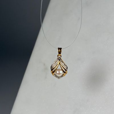 collier orné d'un pendentif en perle et diamants sur un fond blanc