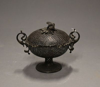an old metal bowl with a bird on it sitting on top of a table