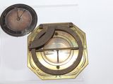 a clock and a compass on display on a white surface