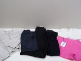 three pairs of black, pink, and white sweatpants laying on top of a bed
