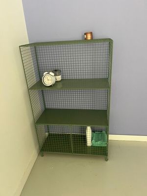une étagère verte sur laquelle se trouve une horloge, dans une pièce