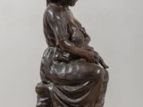 bronze statue of a woman sitting on a stool with a cat