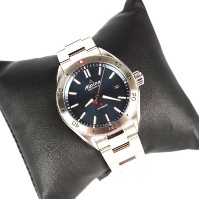 une photo d'une montre posée sur un coussin noir