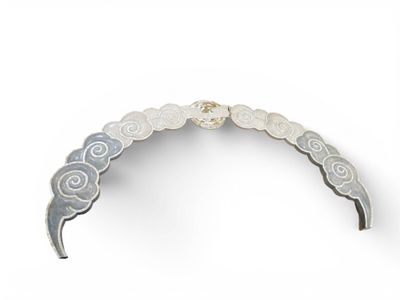 un gros plan d'un collier argenté et blanc posé sur une surface blanche