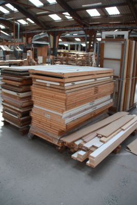several stacks of wood sit in a large warehouse with a lot of windows