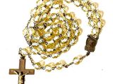 yellow glass rosary with a wooden cross on a white background