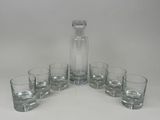 six verres et une carafe posés sur une table