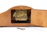 a small wooden clock with a key in the middle of it