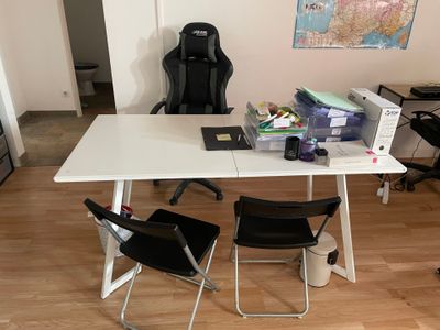 une table blanche avec deux chaises et un ordinateur portable posé dessus