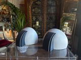 two white and black helmets sitting on top of a clear table