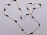 a close up of a necklace with pearls and black beads