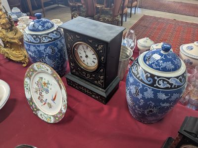 a table with a red table cloth and a blue and white vase and a clock