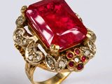 une image représentant une bague ornée d'une pierre rouge entourée de diamants