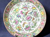 une assiette ornée de fleurs et d'oiseaux, posée sur un socle