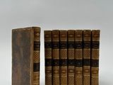 Trois livres sont posés sur une surface blanche ; l'un d'entre eux est ouvert.