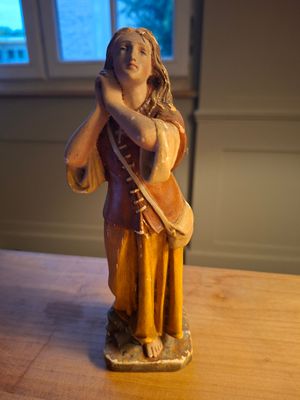 une figurine représentant une femme tenant un sac, posée sur une table