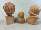 three clay busts of women and a boy sitting on a table