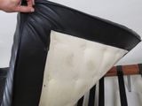 a person holding a mattress on top of a black leather chair