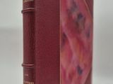 un vieux livre à la couverture rouge posé sur une surface blanche