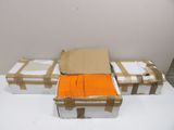 trois cartons contenant des t-shirts orange, posés sur une table