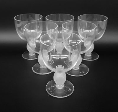 six clear wine glasses sitting on top of a black table