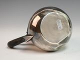 a silver cup with a handle on a white surface