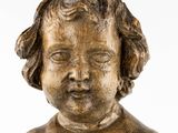 an antique wooden busturine of a child with curly hair and eyes closed