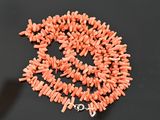 an orange coral bead necklace with a silver clasp on a black surface