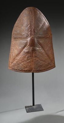 une image représentant un masque en bois posé sur un socle, sur fond gris