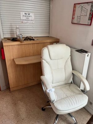 une chaise de bureau blanche placée devant un bureau et un radiateur
