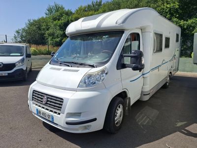 un camping-car blanc garé sur un parking à côté d'autres véhicules