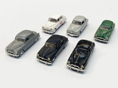 plusieurs petites voitures sont alignées sur une surface blanche
