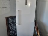 un réfrigérateur blanc dans une pièce où se trouve un tableau noir accroché au mur