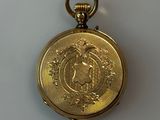 a gold pocket watch with a medallion on it