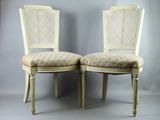 pair of white cane back chairs with beige upholstered cushions