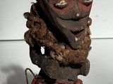 une vieille statue en bois représentant un homme barbu coiffé d'un chapeau