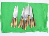 several knives are lined up on a green cloth on a white surface