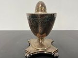 silver plated egg on stand on black table with white background