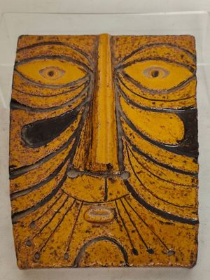 un masque jaune et noir exposé dans une vitrine
