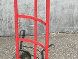 un diable rouge avec une poignée noire dans la rue