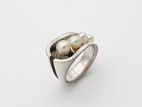 a close up of a ring with two pearls on it