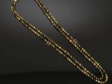 a gold and black beaded necklace on a black background