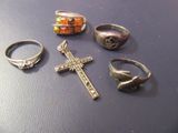 cinq bagues différentes et une croix posées sur une table