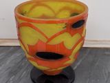 un vase jaune et orange posé sur un socle noir
