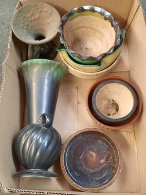 une boîte remplie de vases et de bols posée par terre