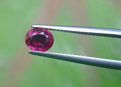 un gros plan sur une pince tenant un diamant rose