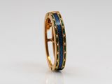 un gros plan d'une bague en or ornée d'incrustations d'émail bleu et vert