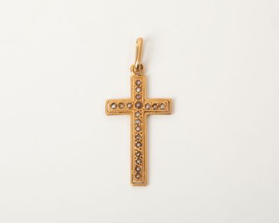 un pendentif en forme de croix en or, orné de petits diamants sur fond blanc