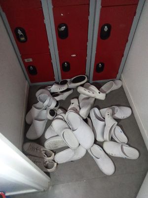 de nombreuses paires de chaussures blanches dans une pièce aux portes rouges