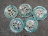 quatre assiettes bleues et blanches ornées de fleurs, posées par terre